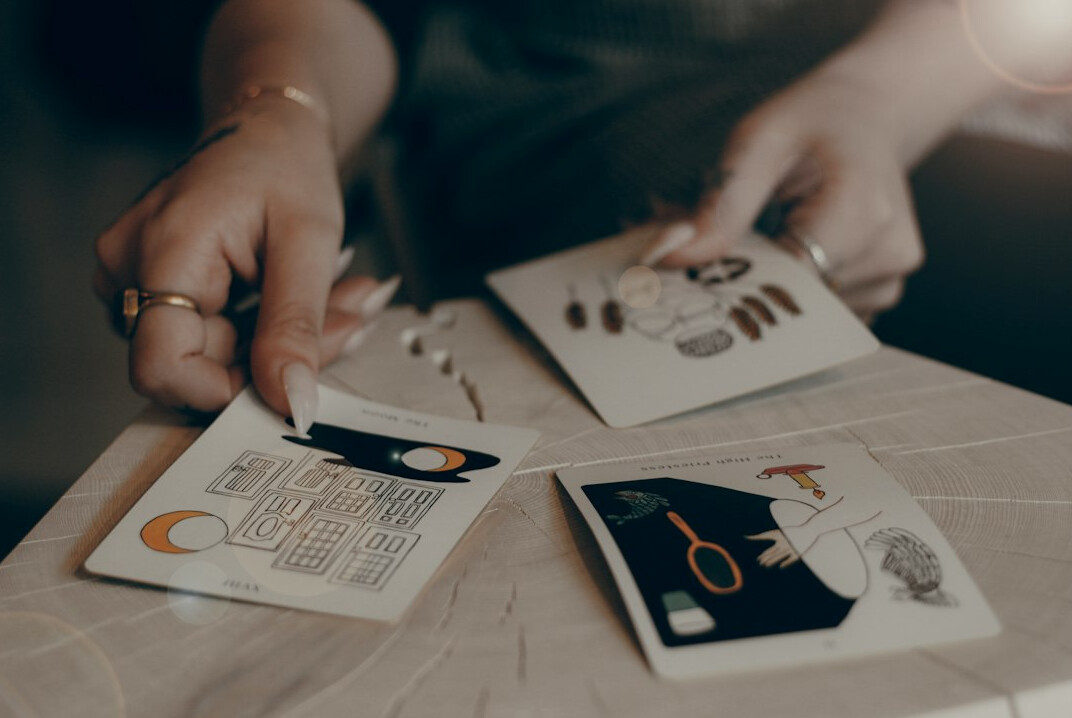 Hands reviewing printed photographs and contact sheets on a wooden desk